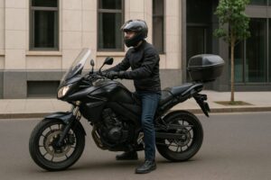 都会の街角で、大型バイクにまたがり発進準備をするライダーの横長写真。